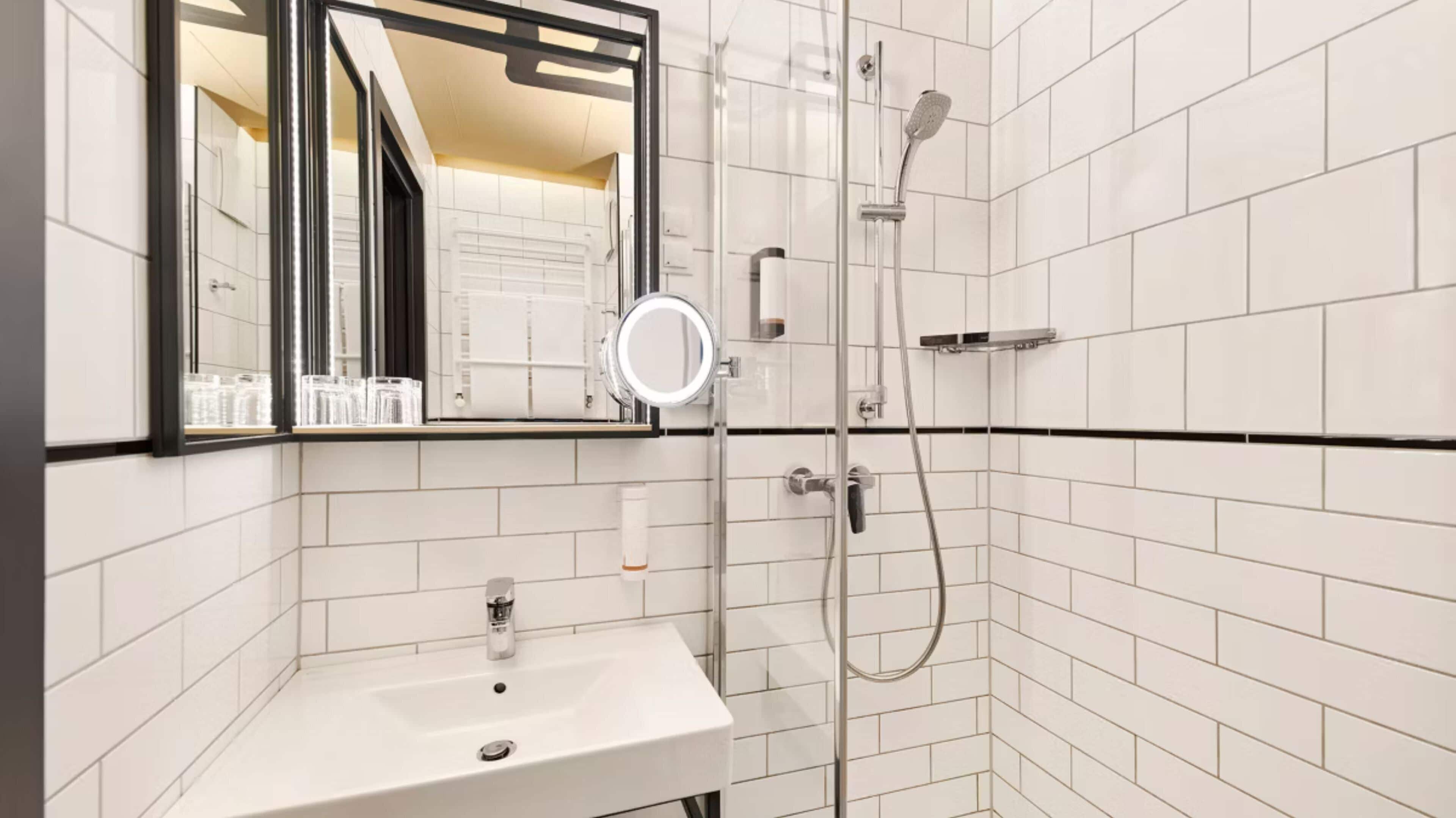 A bathroom with a white sink, a mirror, and a shower.