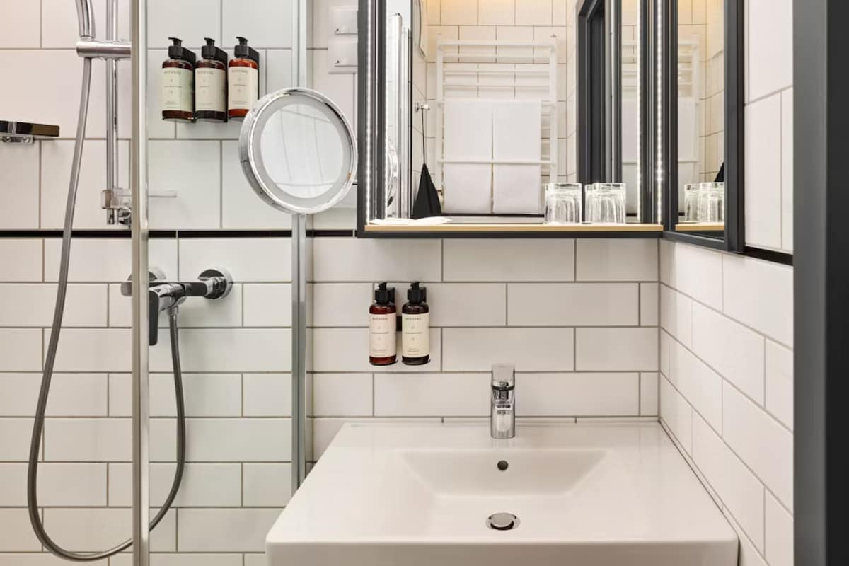 A bathroom with a white sink, a mirror, a towel rack, and toiletries.