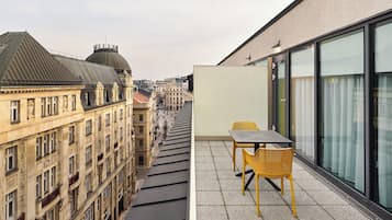 A modern building with a rooftop terrace featuring a table and chairs.