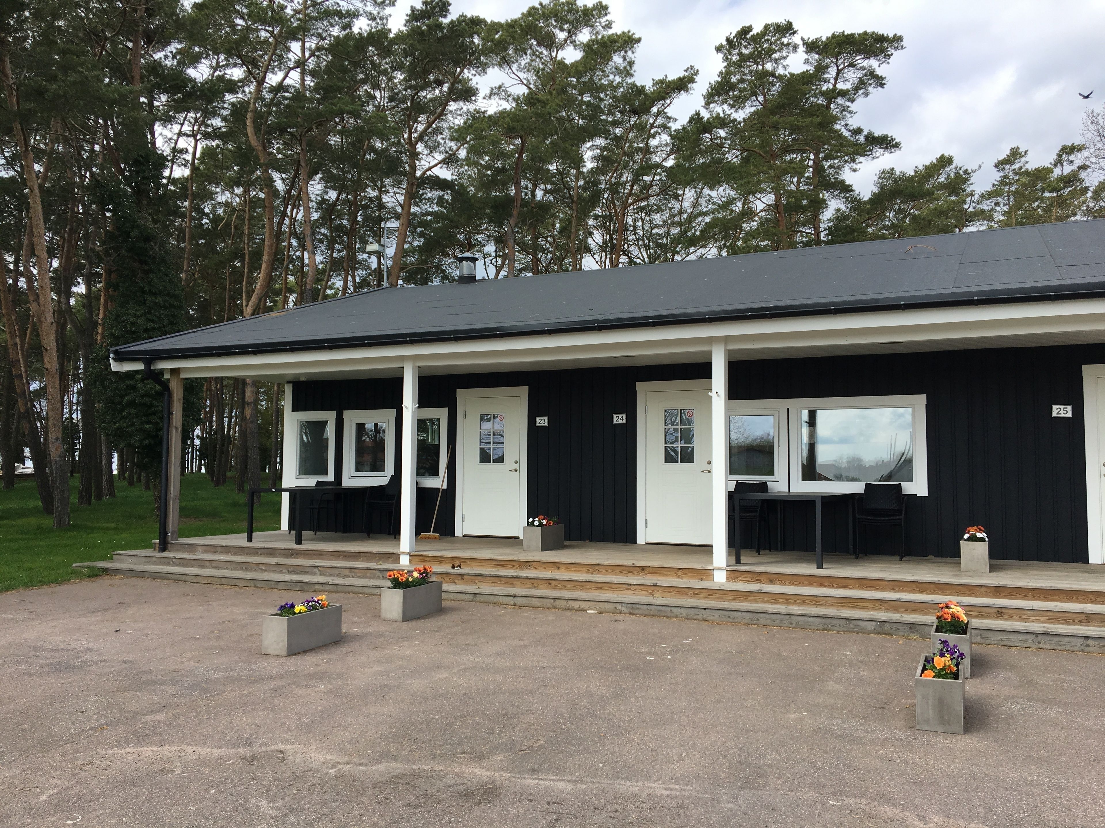 En byggnad med en veranda, numrerade dörrar och utomhusplatser.