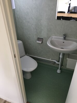 A small bathroom with a toilet, sink, and a mirror above the sink. - Kapelludden Camping & Stugor (Borgholm)