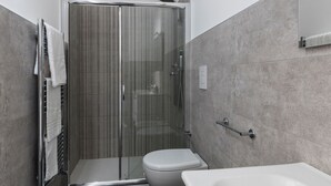 Een moderne badkamer met een douchecabine van glas, een wit toilet en een bad.