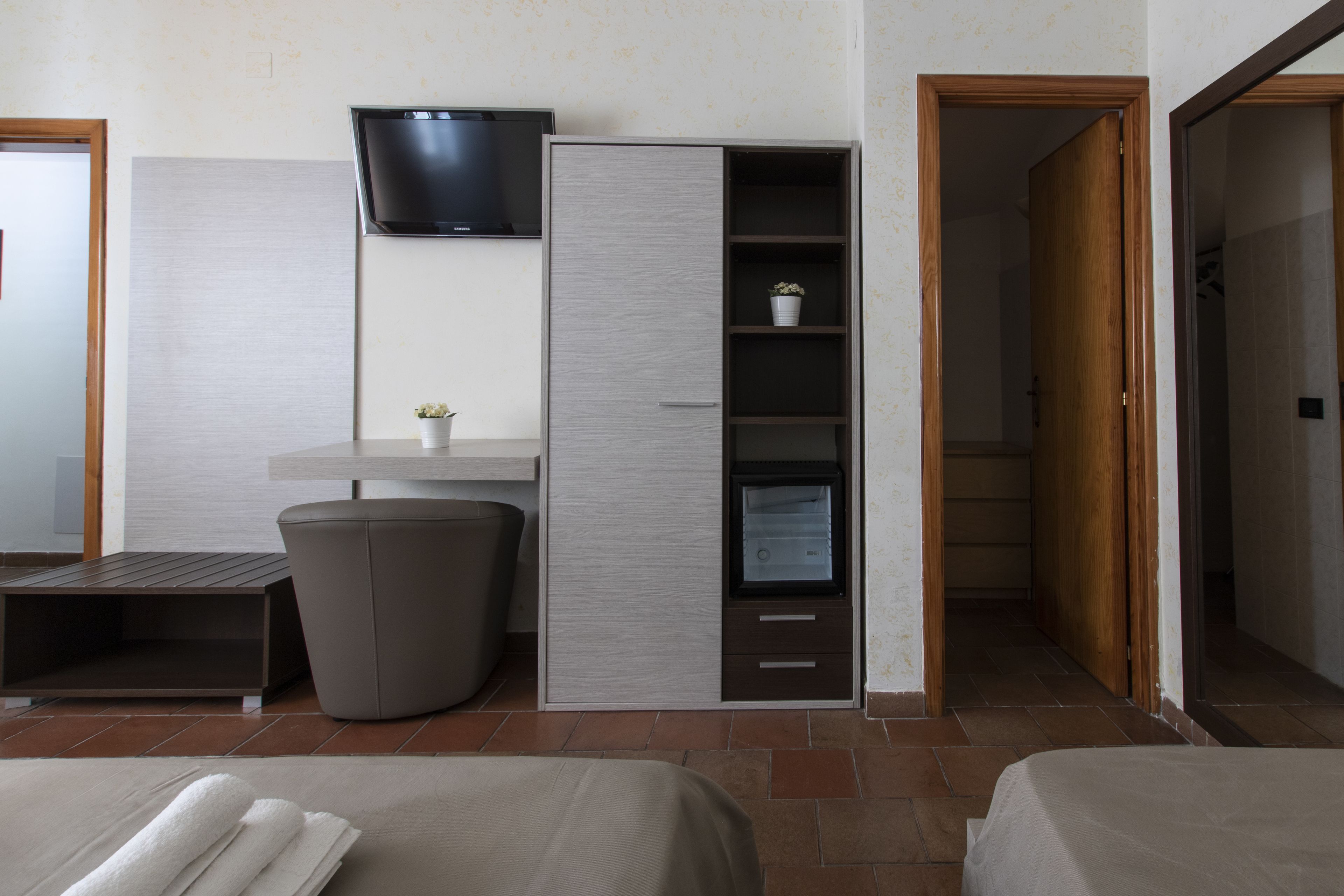 Una habitación de hotel con una cama, un armario, un televisor y un cubo de basura.