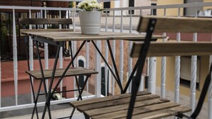 Een balkon met een houten tafel en stoelen, een bloempot en een witte balustrade.