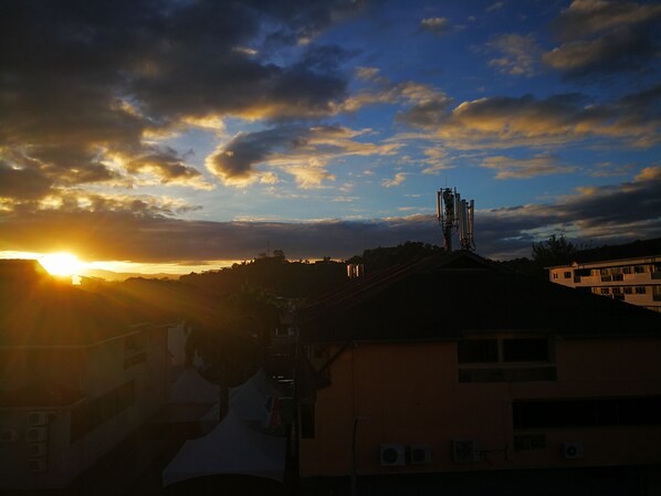 A sunset over a cityscape with buildings and a communication tower.