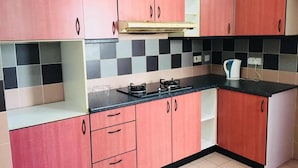 A kitchen with pink cabinets, a black countertop, and a tiled backsplash. - KK City HomeSuite at KK City Center 2 (Kota Kinabalu)