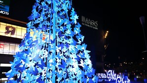 A large illuminated Christmas tree with blue butterflies, located in a shopping area with visible store signs. - KK City HomeSuite at KK City Center 2 (Kota Kinabalu)