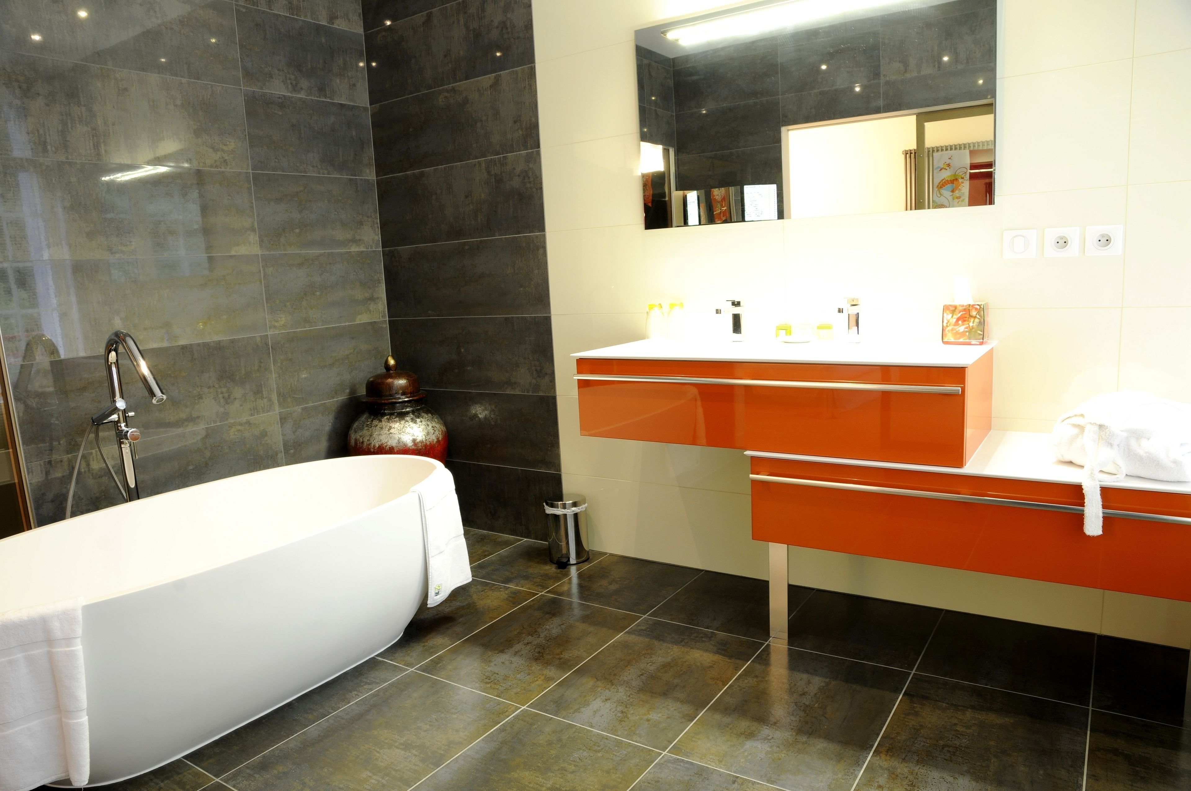 Un bagno moderno con una vasca freestanding, un mobile lavabo con specchio e un pavimento piastrellato.