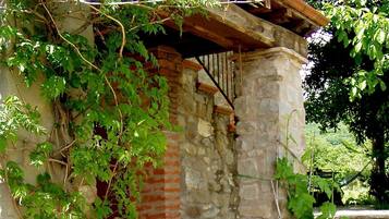 Un edificio in pietra con una sedia a dondolo in legno e una pianta in vaso.