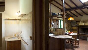 Una cucina rustica con un tavolo di legno, un lavello e un muro in pietra.