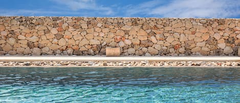 Una piscina al aire libre, sombrillas, sillones reclinables de piscina