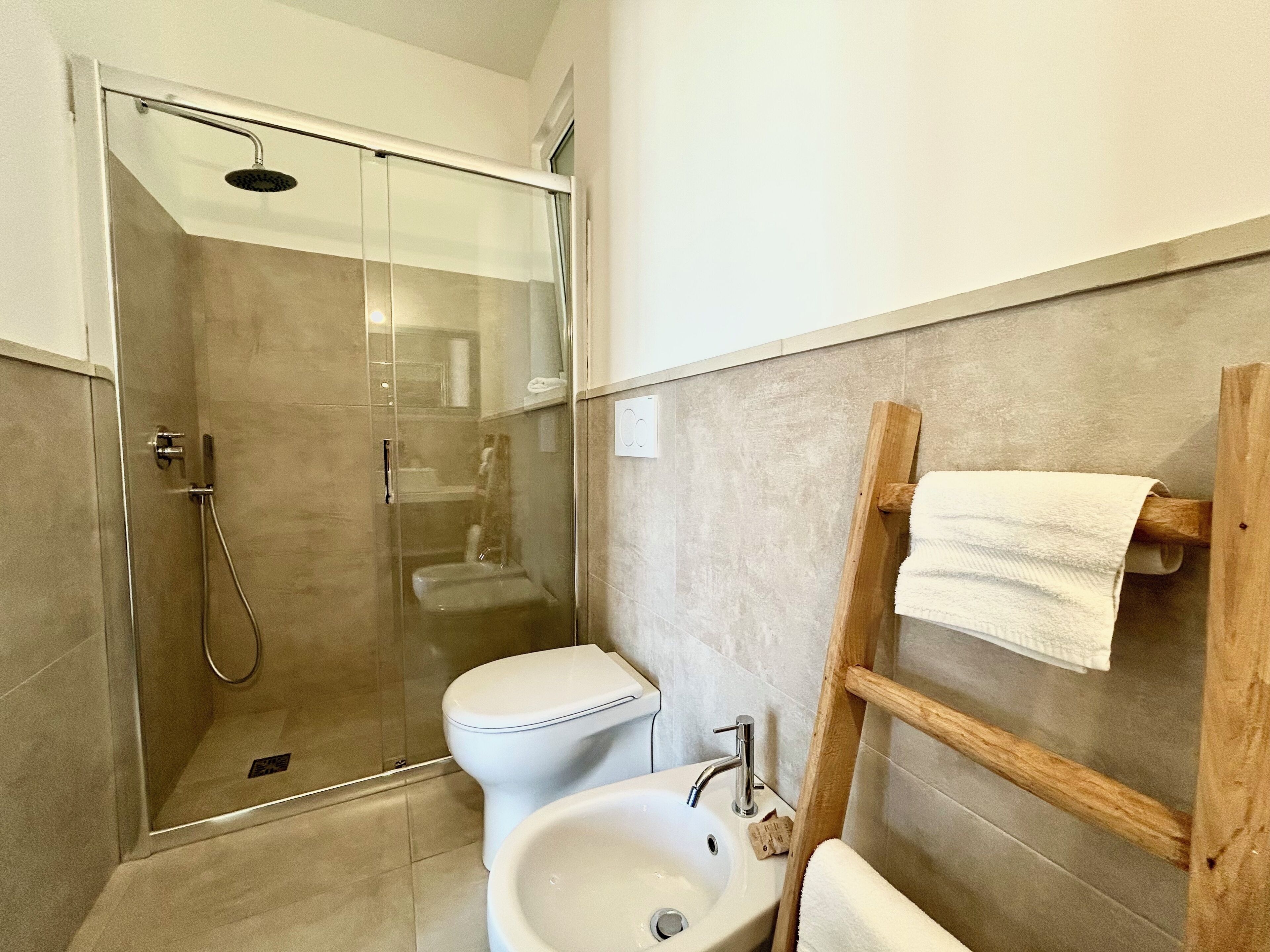 Un baño moderno con ducha envuelta en vidrio, inodoro y lavamanos.