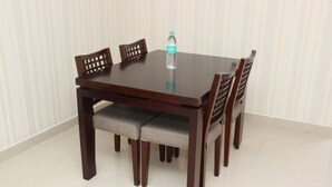 A dining table with four chairs, a bottle of water, and a white tiled floor. - Saaral Resorts (Tarangambadi)