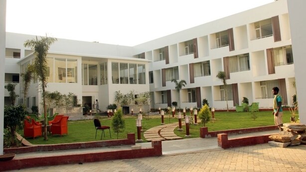 A modern building with multiple floors, large windows, and a courtyard with seating and greenery. - Saaral Resorts (Tarangambadi)