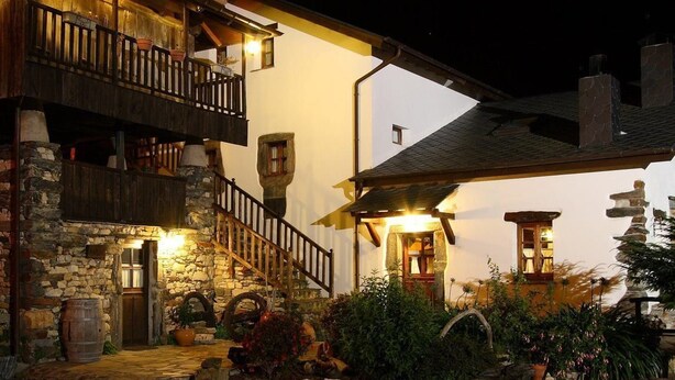 A rustic building with a stone facade, wooden balconies, and a well-lit entrance. - Casa La Fonte (Valdes)
