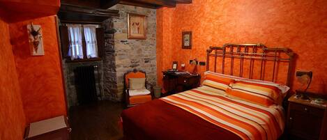 A cozy bedroom with a wooden bed, a stone wall, and a rustic ambiance.