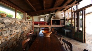 A rustic stone wall, wooden ceiling beams, a stone fireplace, and a large terracotta pot on a wooden table. - Casa La Fonte (Valdes)