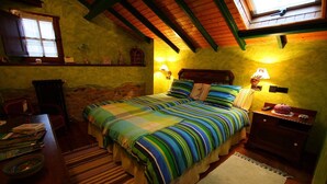 A cozy bedroom with a large bed, wooden headboard, two bedside lamps, and a small table with books. - Casa La Fonte (Valdes)