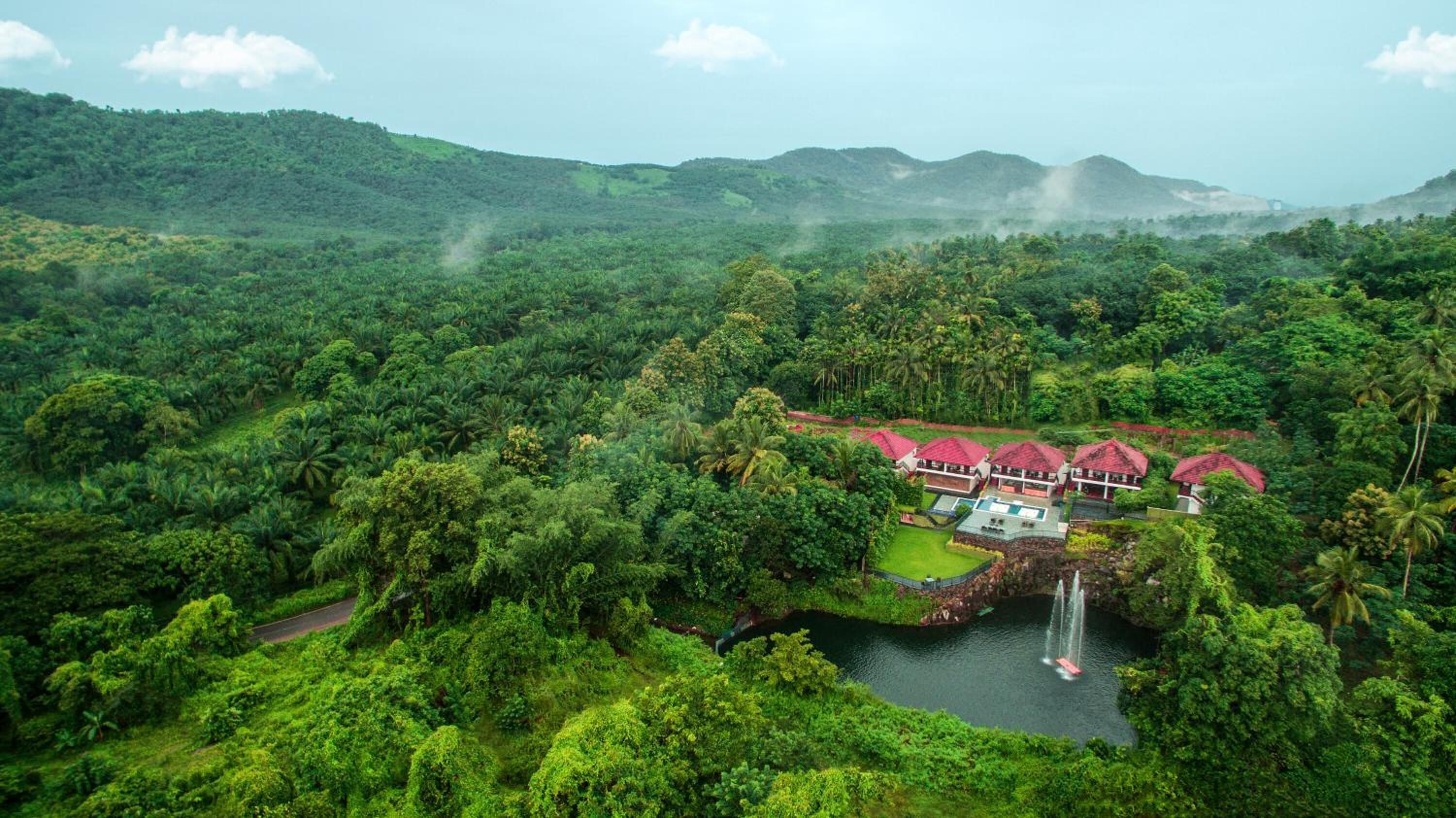 A lush, tropical resort with a pool, a waterfall, and a view of the surrounding forest.