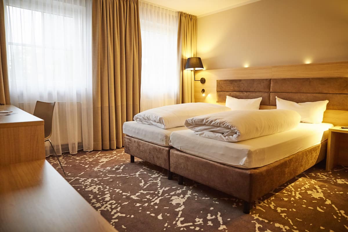 Habitación de hotel con una cama grande, un escritorio y una lámpara.