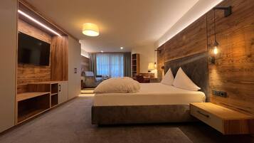 Ein modernes Hotelzimmer mit einem großen Bett, Holzvertäfelung, einem Fernseher und einem Schreibtisch.