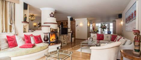 Amplia sala de estar con chimenea, sofás blancos y cojines rojos.