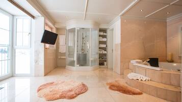 A modern bathroom with a glass-enclosed shower, a marble-tiled floor, and a vanity with a bathtub.