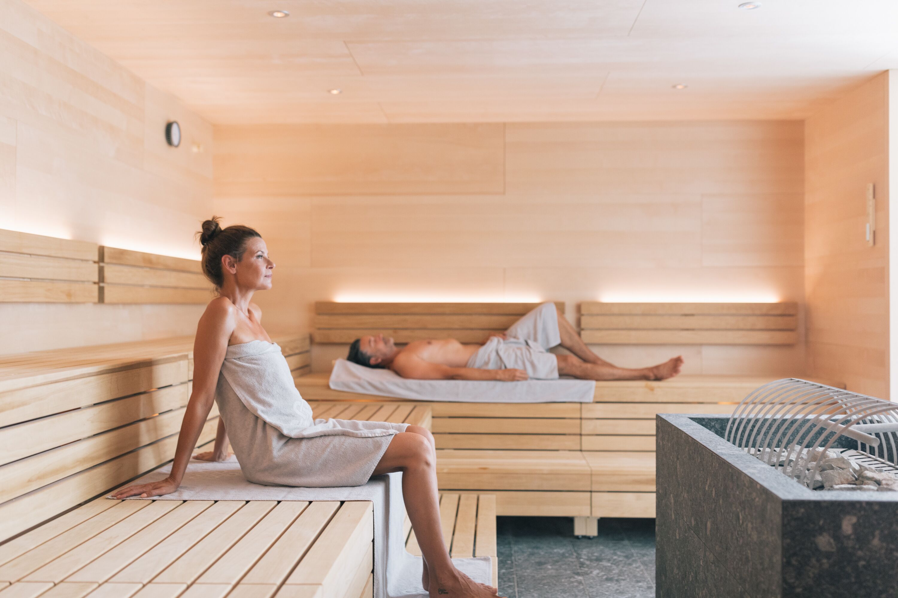 Un sauna con bancos de madera y una pileta de piedra.