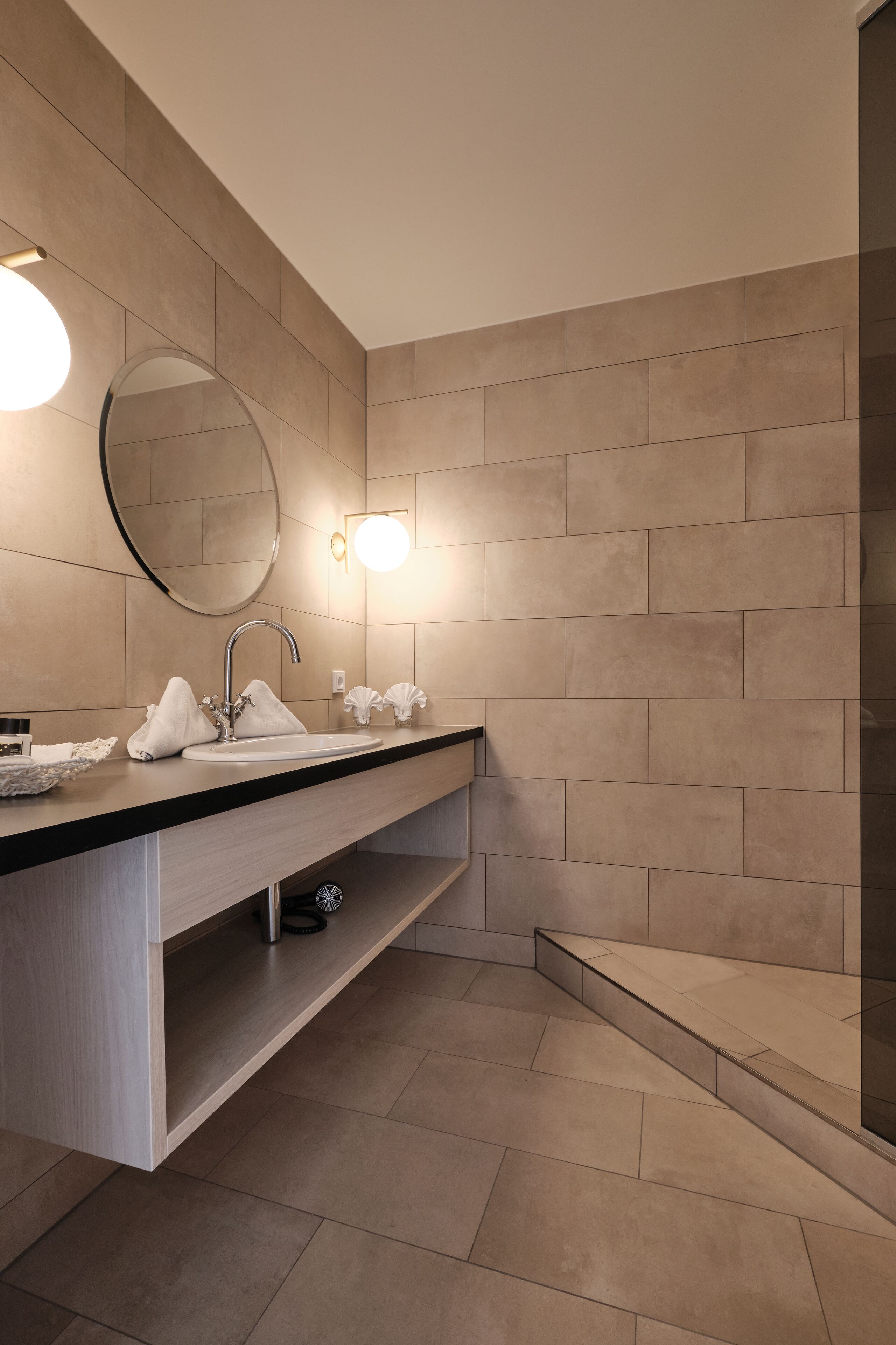 Un baño moderno con un espejo grande, un lavamanos y una zona de ducha.