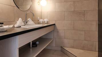 Un baño moderno con un espejo grande, un lavamanos y una zona de ducha.