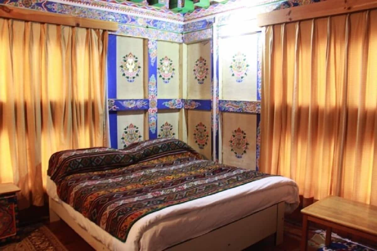 Una habitación tradicional con cama, cortinas y paneles decorativos en la pared.