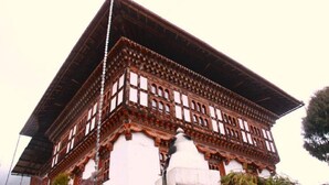 A traditional building with a steeply pitched roof, wooden lattice detailing, and a white base. - Thegchen Phodrang Lodge (Wangdue Phodrang)