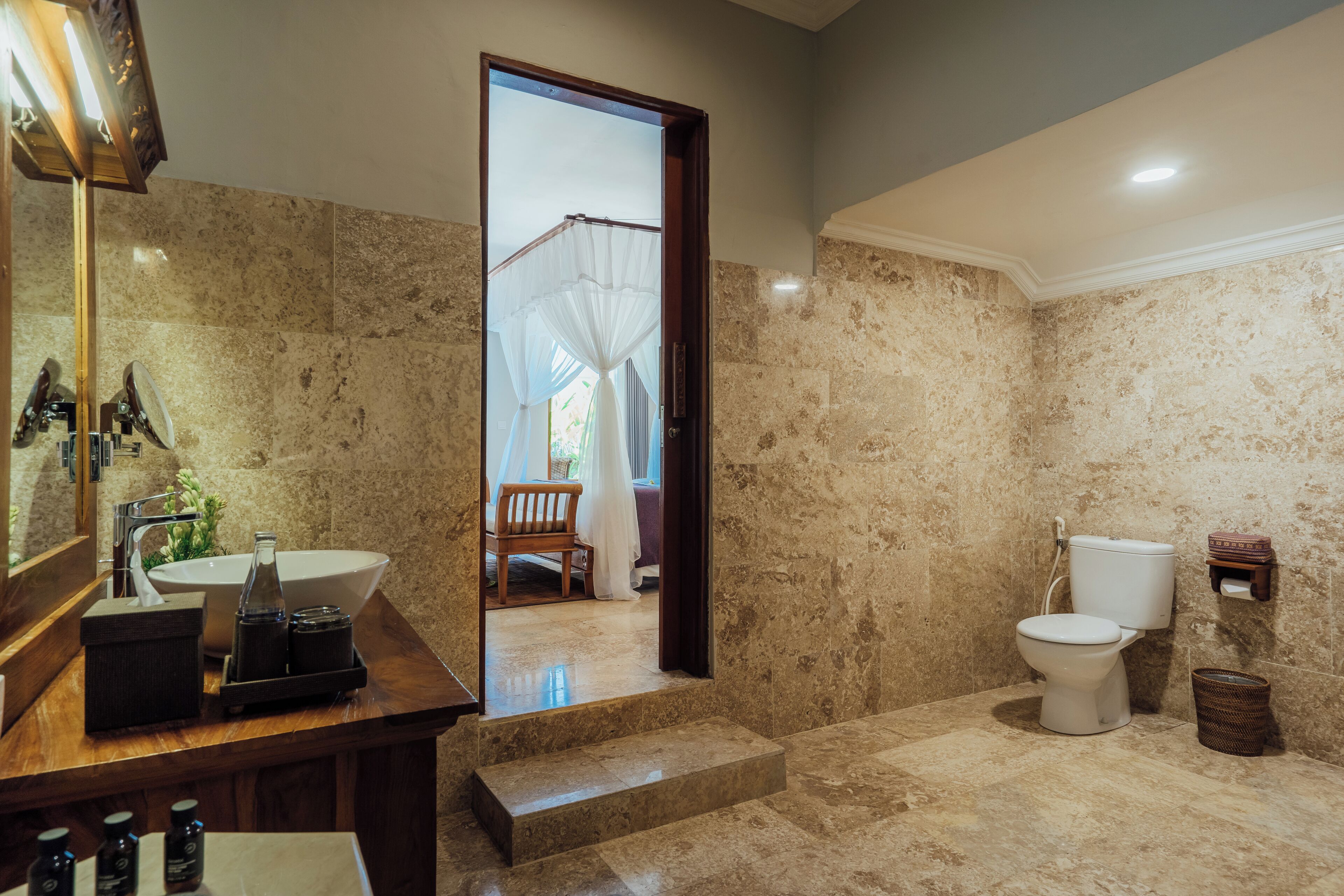A bathroom with a marble floor, a sink, a toilet, and a mirror.