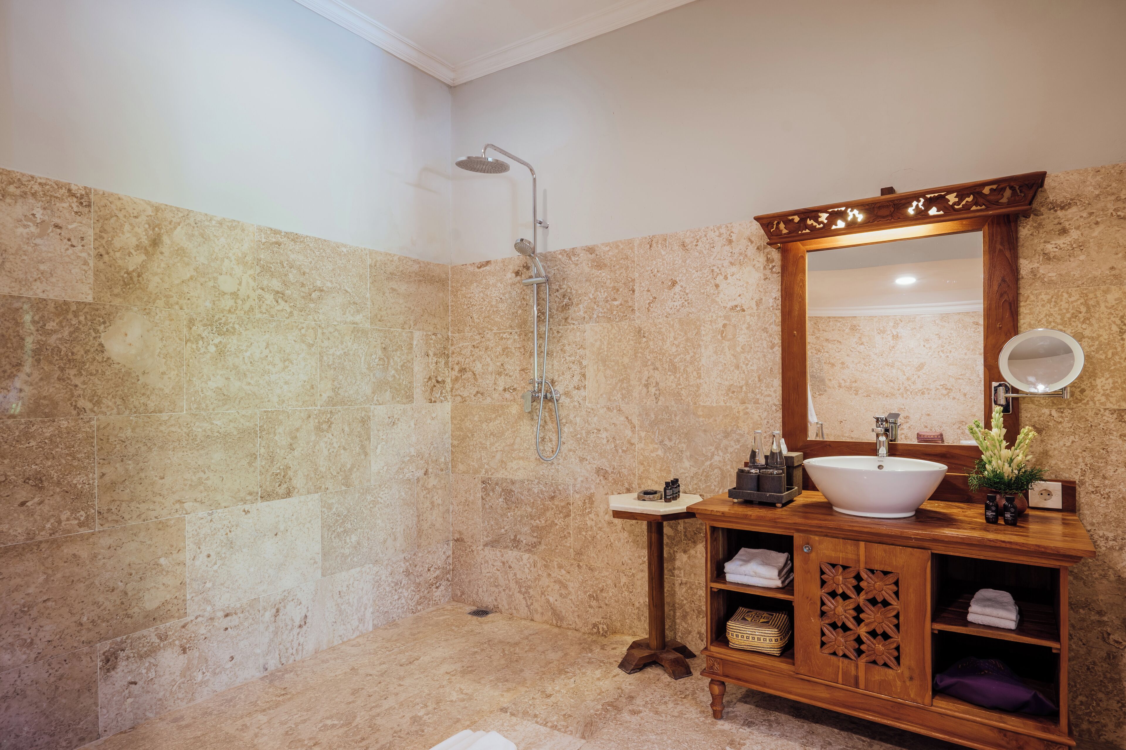 A bathroom with a large mirror, a wooden vanity, a sink, and a shower.