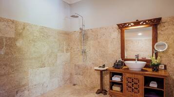 A bathroom with a large mirror, a wooden vanity, a sink, and a shower.