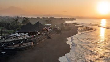 A beachfront resort with a long pier, umbrellas, and seating areas.