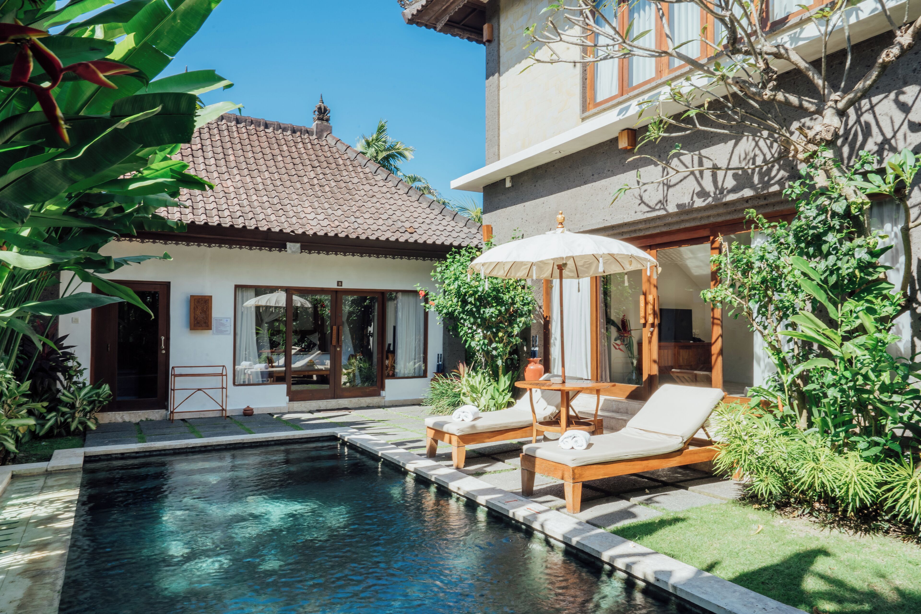 Un espace piscine avec des chaises longues et une pergola.