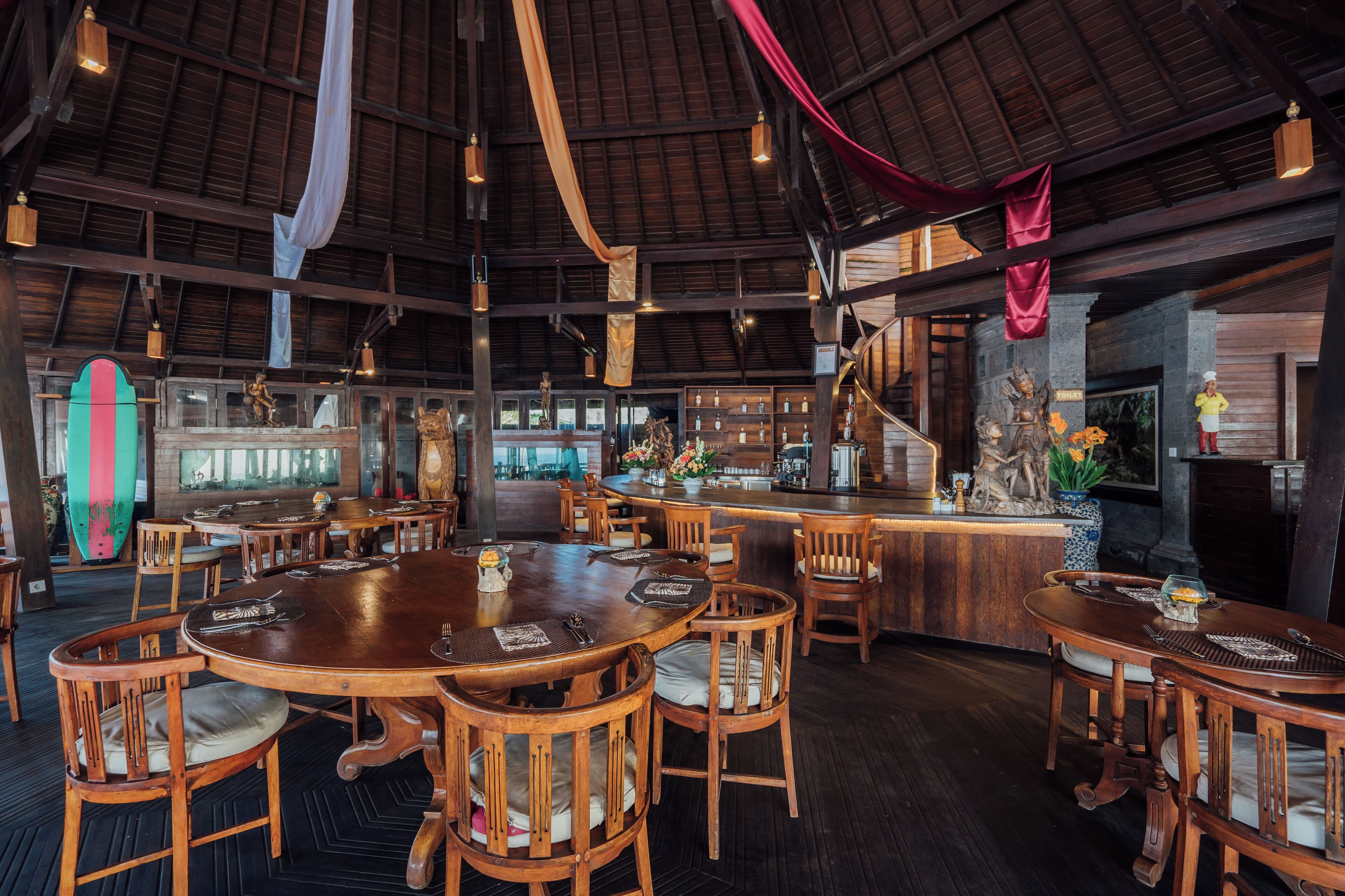 Un restaurante con mesas y sillas de madera, una zona de bar y una chimenea de piedra.