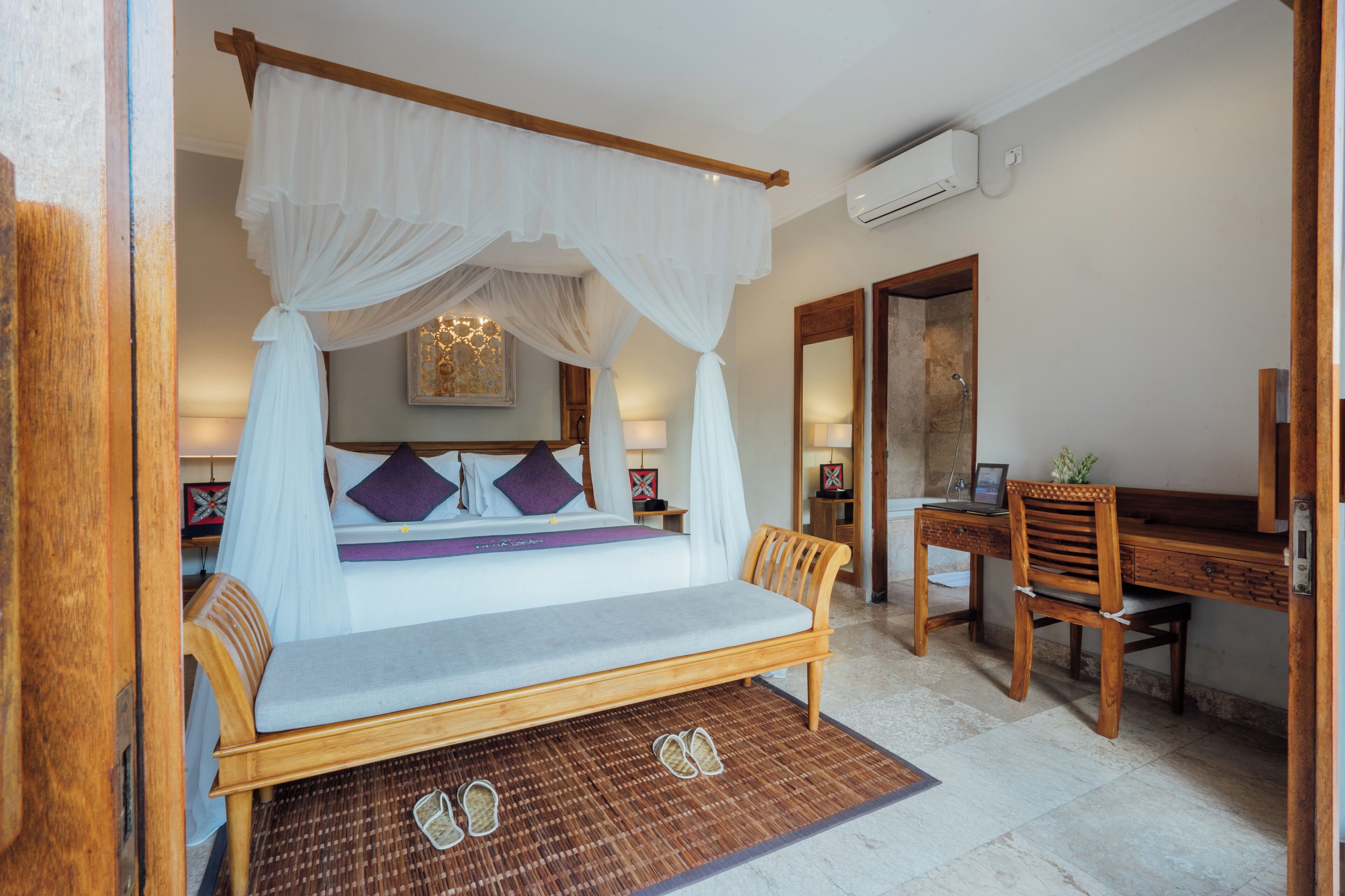 A bedroom with a four-poster bed, a desk with a chair, and a large mirror.