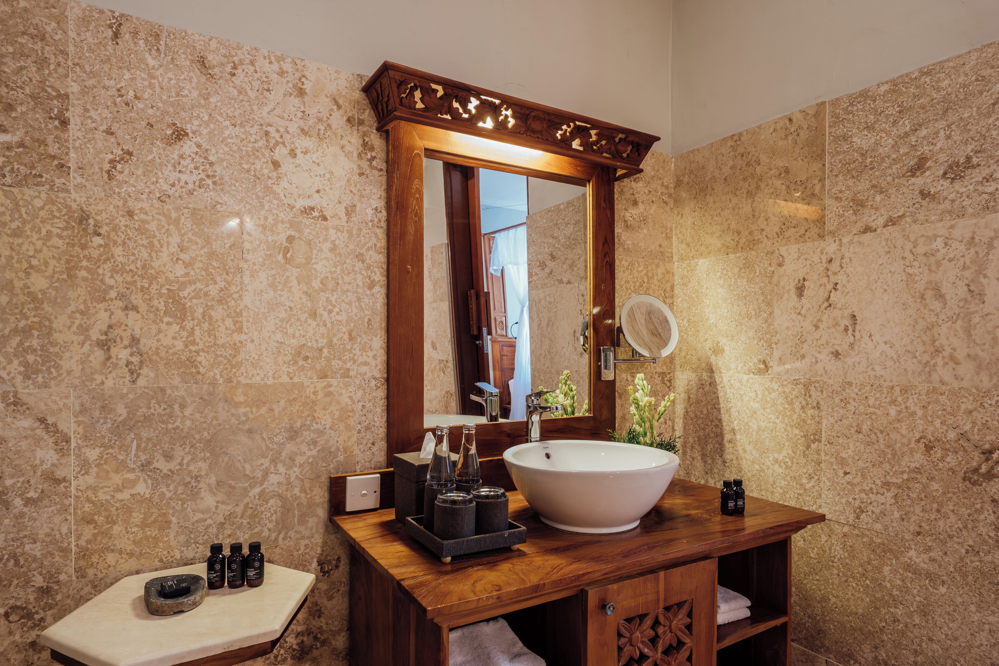 Un bagno con un lavandino grande e indipendente, un mobile contenitore in legno, uno specchio con cornice decorativa e una piccola mensola con articoli da toilette.