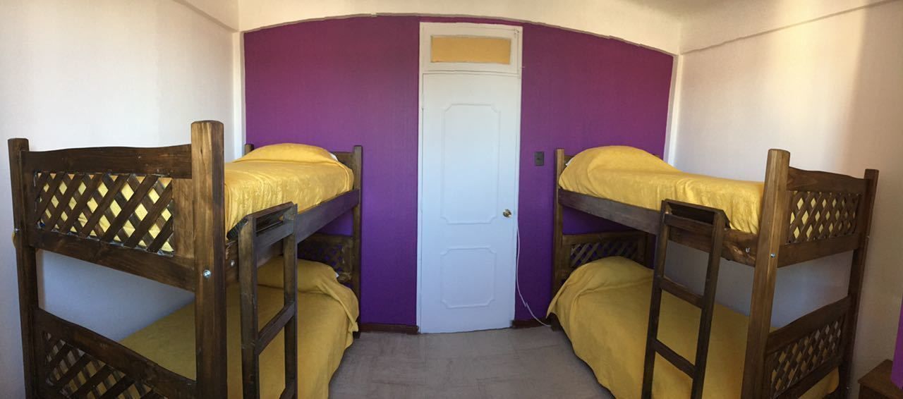Una habitación con dos literas, una puerta y paredes moradas.