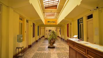 A hotel corridor with a central plant, a reception desk, and a sign reading "Hotel Puerto."