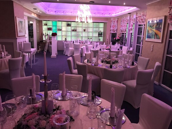 A banquet hall with round tables set for a formal event, featuring white chairs and table settings with glassware and floral centerpieces. - Hotel Haus Roedgen (Wilnsdorf)