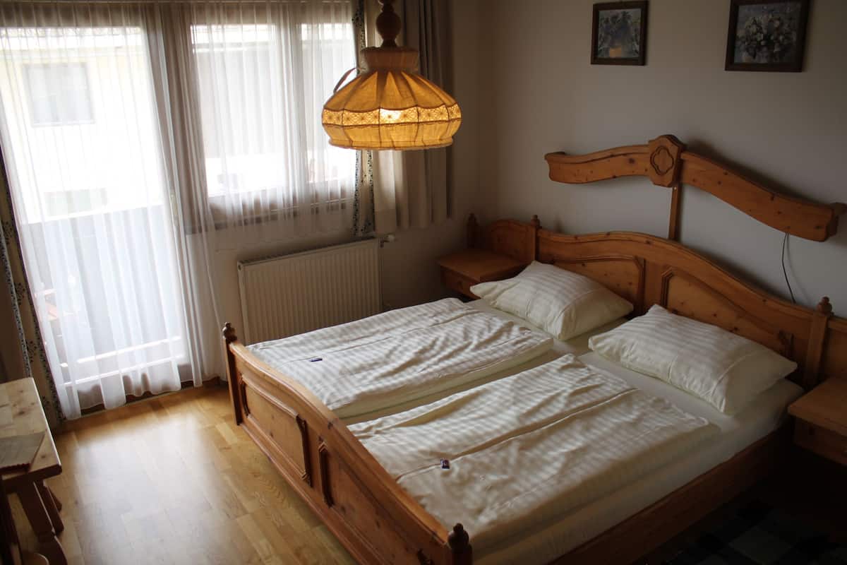 A double bed with a wooden headboard, a bedside table, and a hanging lamp.