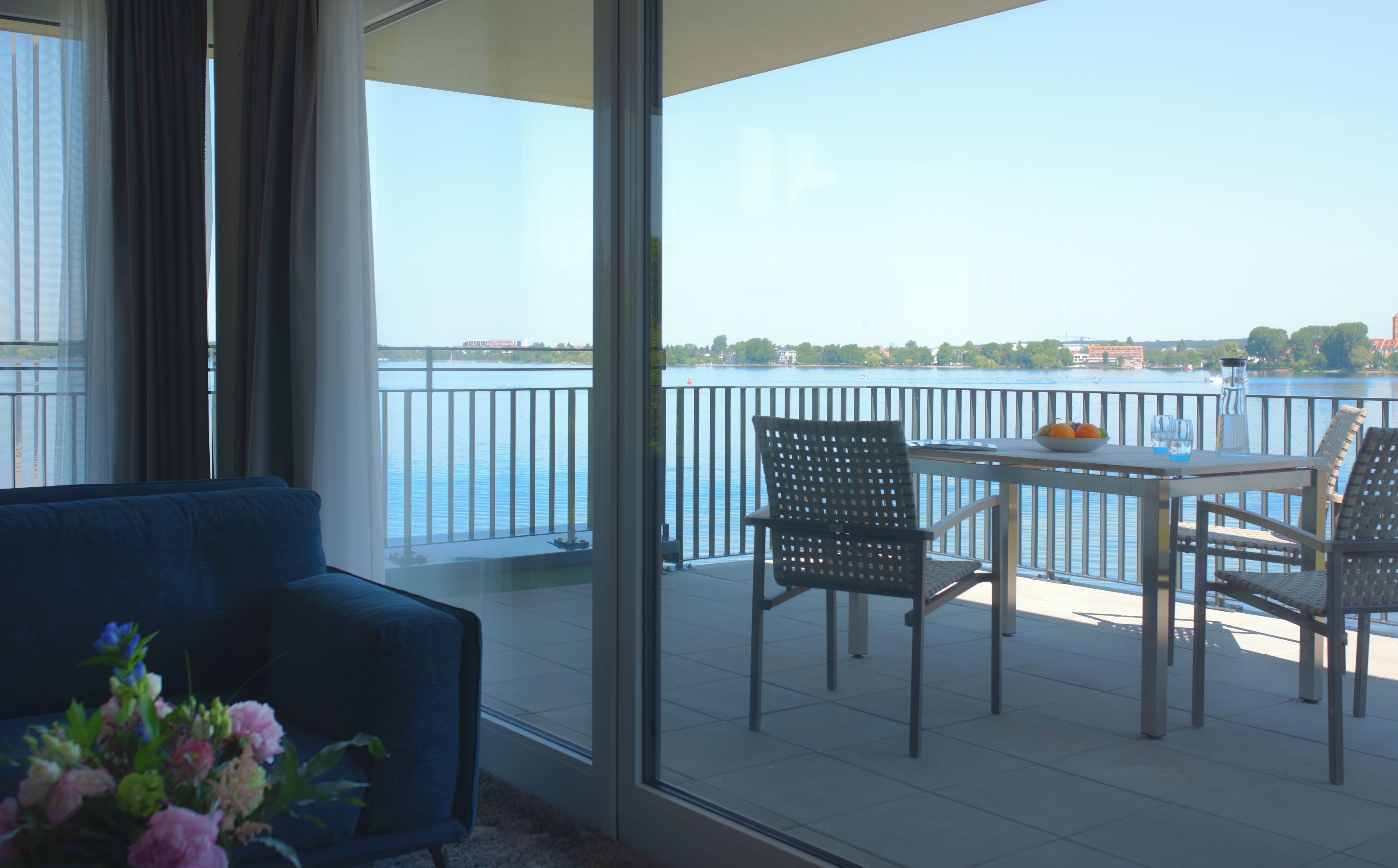 A balcony with a table, chairs, and a view of a body of water.