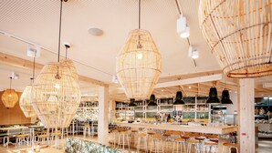 A modern interior with high ceilings, exposed wooden beams, and a central bar area with stools and bar stools. - Maremüritz Yachthafen Resort (Waren (Müritz))