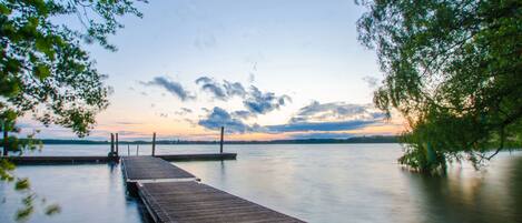 A wooden pier extending into calm water with a clear sky and distant land.