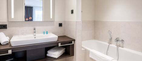 Une salle de bain moderne avec un grand lavabo, un miroir et une baignoire.