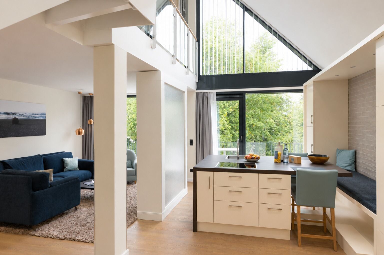 A modern kitchen with a large window, a dining area with a bench, and a living room with a sofa.