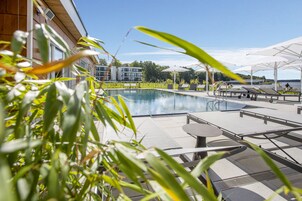 Una piscina al aire libre, una piscina climatizada, sombrillas